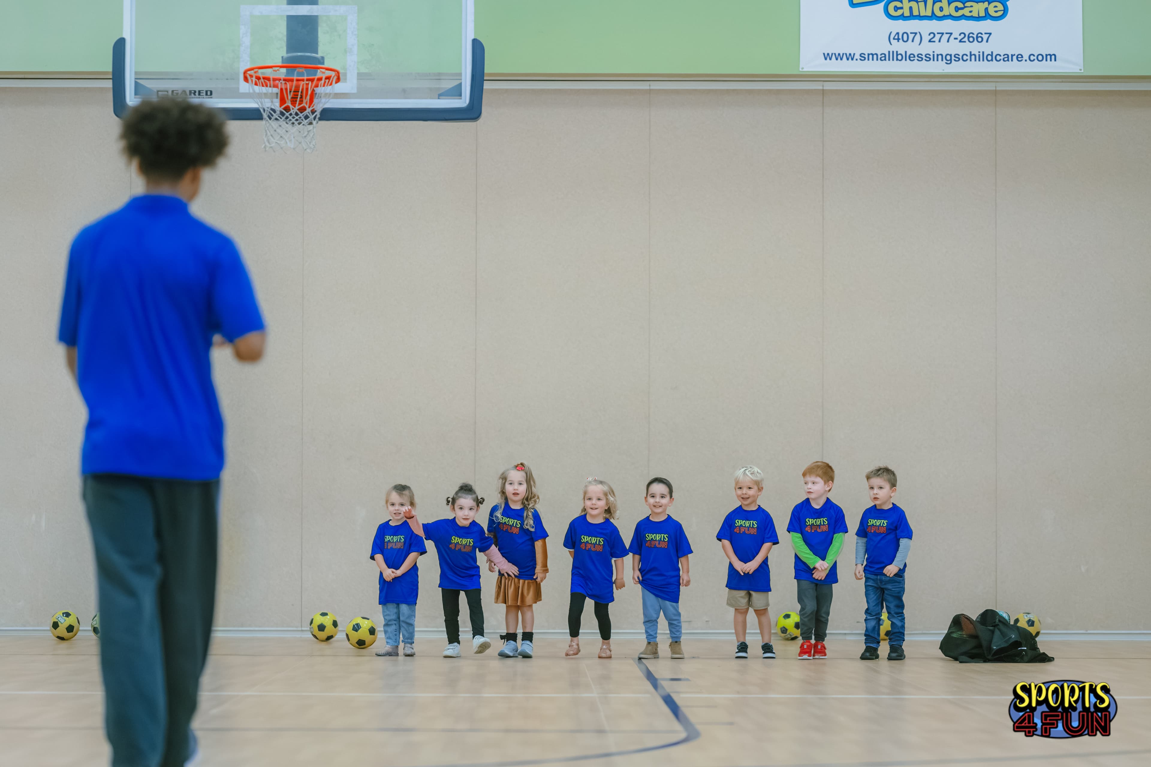 Sports4Fun coach with a group of children lined up in a gym